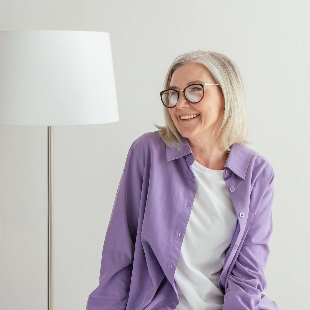 A Woman in Purple Long Sleeves Smiling while Wearing Eyeglasses